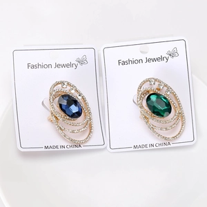 Detailed close-up of retro gold-plated oval brooches with blue and emerald green gemstones