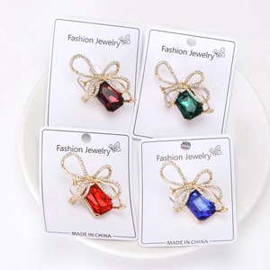 Detailed macro view of crystal bow brooches in four colors on a white ceramic tray