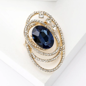 Macro shot of deep blue oval gemstone brooch with white crystal encrusted layers on gold