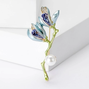 Elegant lily brooch with blue petals, purple crystals, and a large pearl on a white base