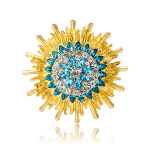 Elegant gold sunflower brooch with blue and white crystals in a radial flower design