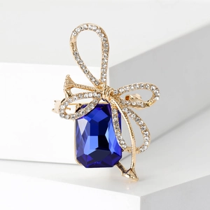 Detail of crystal bow brooch featuring a large rectangular blue sapphire and rhinestones