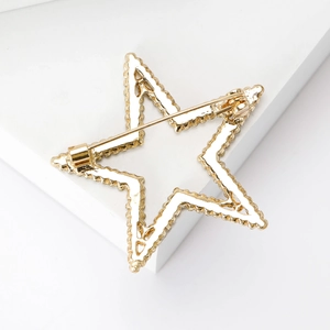Golden star brooch with rhinestone cutout and secure pin clasp on white background