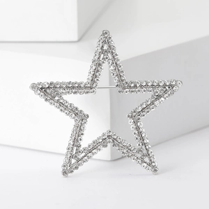 Close-up of a silver pentagram brooch featuring sparkling rhinestones and metal pin detail