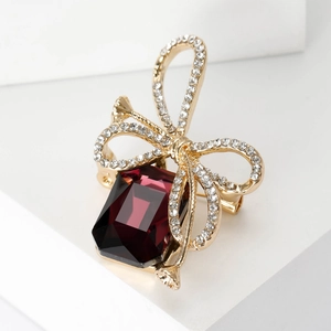 Elegant gold bow brooch with a large wine red rectangular gemstone and white crystals