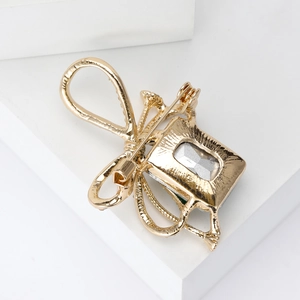 Elegant gold bow brooch with a large rectangular crystal gemstone and polished finish