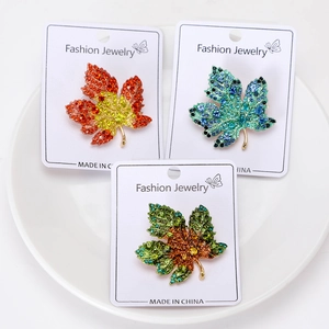 Vue détaillée de trois broches en forme de feuille d'érable serties de strass colorés