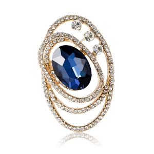 Elegant vintage oval brooch with deep blue crystal and golden zircon inlay on white background