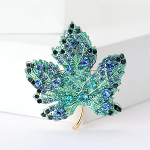 Vue détaillée de la broche feuille d'érable dorée avec dégradé de cristaux bleus