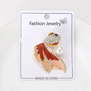 Dettaglio spilla pesce rosso con smalto rosso, strass brillanti e accento di perla