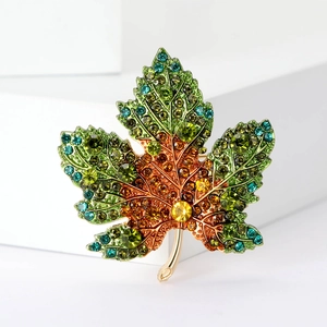 Macro d'une broche en forme de feuille d'érable sertie de strass sur base dorée