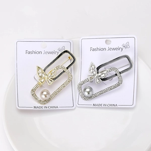 Detail view of butterfly and pearl brooches with geometric frames and crystals