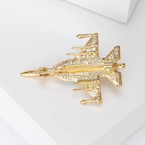 Elegant gold fighter jet brooch with matte texture and pin clasp on white background
