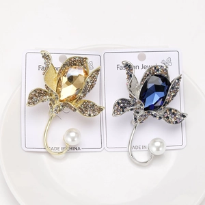 Close-up of gold and silver flower brooches with water-drop crystals and pearls