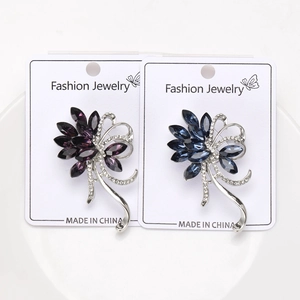 Detailed view of floral rhinestones brooches in purple and blue on white ceramic display