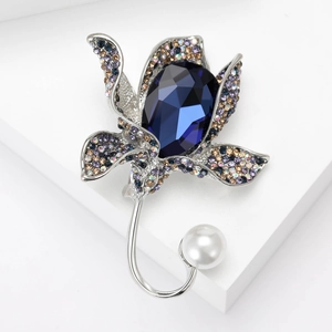 Elegant flower brooch with blue crystal teardrop and white pearl on white podium