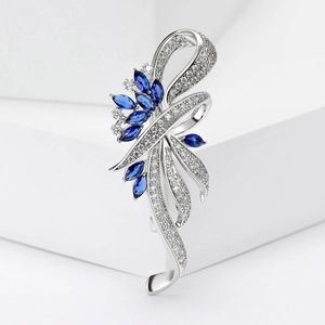 Elegante zilveren broche met blauwe saffier edelstenen en witte zirkoon op witte basis