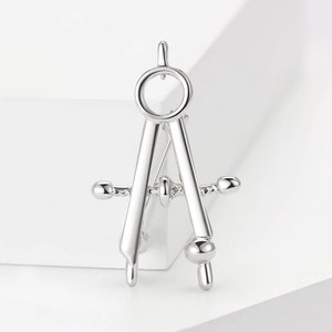 Polished silver alloy compass brooch accessory displayed on white geometric props