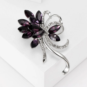 Macro detail of elegant purple rhinestone bauhinia flower brooch on a white stone pedestal