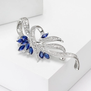 Detail van zilveren broche met blauwe marquise stenen en zirkoon op witte blokken