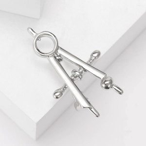 Detailed view of creative silver compass brooch with polished metal finish on white stand