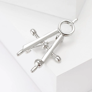 Macro view of a polished silver compass brooch showing detailed metallic stationery design