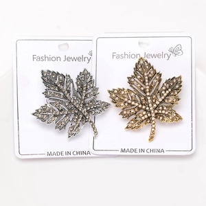 Close-up of maple leaf brooches with rhinestones in antique gold and silver finishes