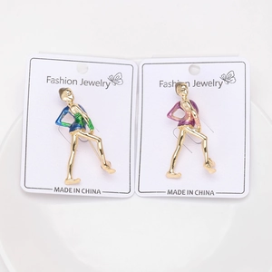 Detailed view of gold ballet dancer brooches with blue and purple enamel on a display card