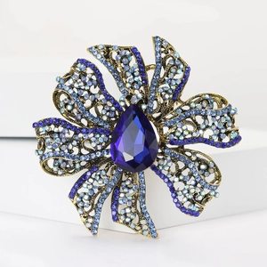 Detailed close-up of a vintage golden floral brooch featuring a large pear-cut blue gemstone