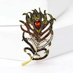 Detailed macro view of vintage peacock feather brooch with gold finish and red crystal stones