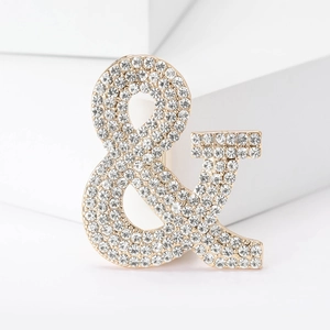 Elegante spilla a forma di e commerciale dorata con strass scintillanti e brillanti