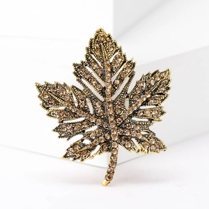 Vintage gold maple leaf brooch with champagne rhinestones on a minimalist white display