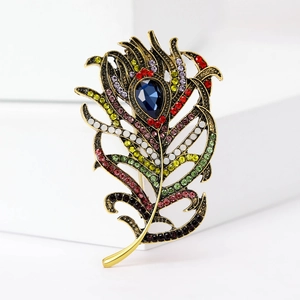 Macro detail of retro peacock feather brooch with colorful rhinestones and blue drop gem