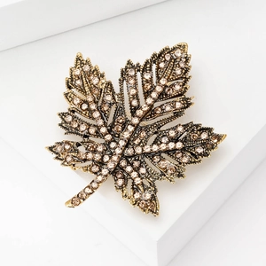 Detailed close-up of maple leaf brooch with champagne rhinestones on a gold metal base