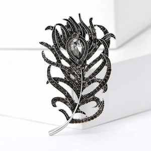 Elegant vintage peacock feather brooch with grey crystals on a white pedestal