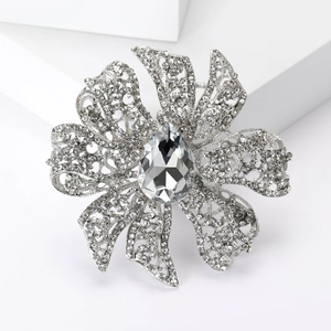 Macro detail of silver floral brooch with pavé rhinestones and a large teardrop crystal