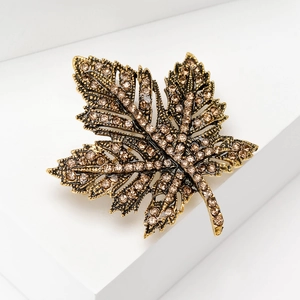 Macro shot of the detailed maple leaf brooch with champagne crystals on a golden metal base