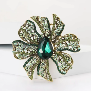 Detailed macro view of vintage flower brooch with green crystals and antique gold finish