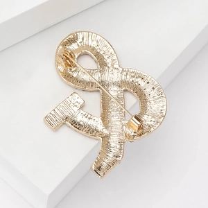 Elegante spilla dorata con chiusura di sicurezza mostrata dal retro su sfondo bianco
