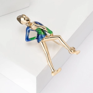 Detail of artistic seated figure brooch with blue and green enamel on gold finish