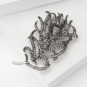 Detailed view of peacock feather brooch with silver alloy, rhinestones and grey gem