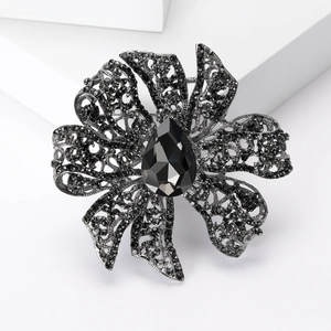 Macro shot of heavy hollow flower brooch with grey crystals on a white pedestal