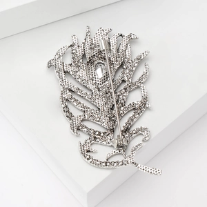 Vintage silver feather brooch with rhinestones and safety pin back on white stand