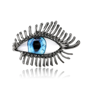 Broche œil grec chic avec iris bleu et longs cils argentés sur fond blanc impeccable