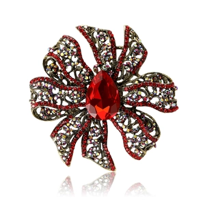 Vintage hollow flower brooch with red rhinestones and crystal teardrop center on white background