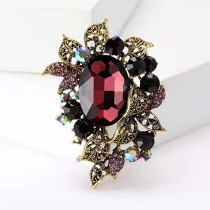 Close-up of vintage gold brooch with red oval crystal and purple rhinestone accents