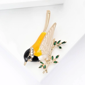 Détail macro d'une broche oiseau en émail jaune dégradé avec strass scintillants