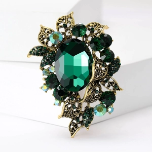 Detailed close-up of a vintage emerald green floral brooch with gold openwork