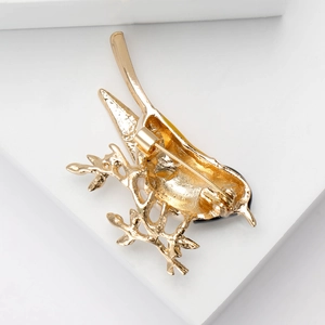 Broche élégante en forme d'oiseau doré avec émail et strass montrée avec le fermoir arrière