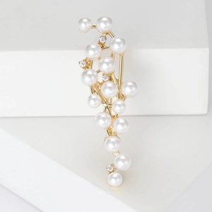 Elegant gold pearl brooch with cluster design on minimalist white display stand